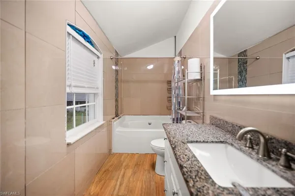 a bathroom with a granite countertop tub sink and mirror
