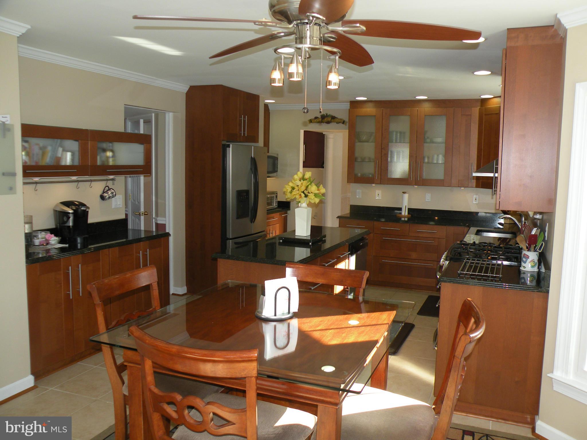 3231 Breckenridge Way Riva, MD 21140 - Photo 3 of 30 a kitchen with stainless steel appliances granite countertop a stove a refrigerator a sink a dining table and chairs with wooden floor