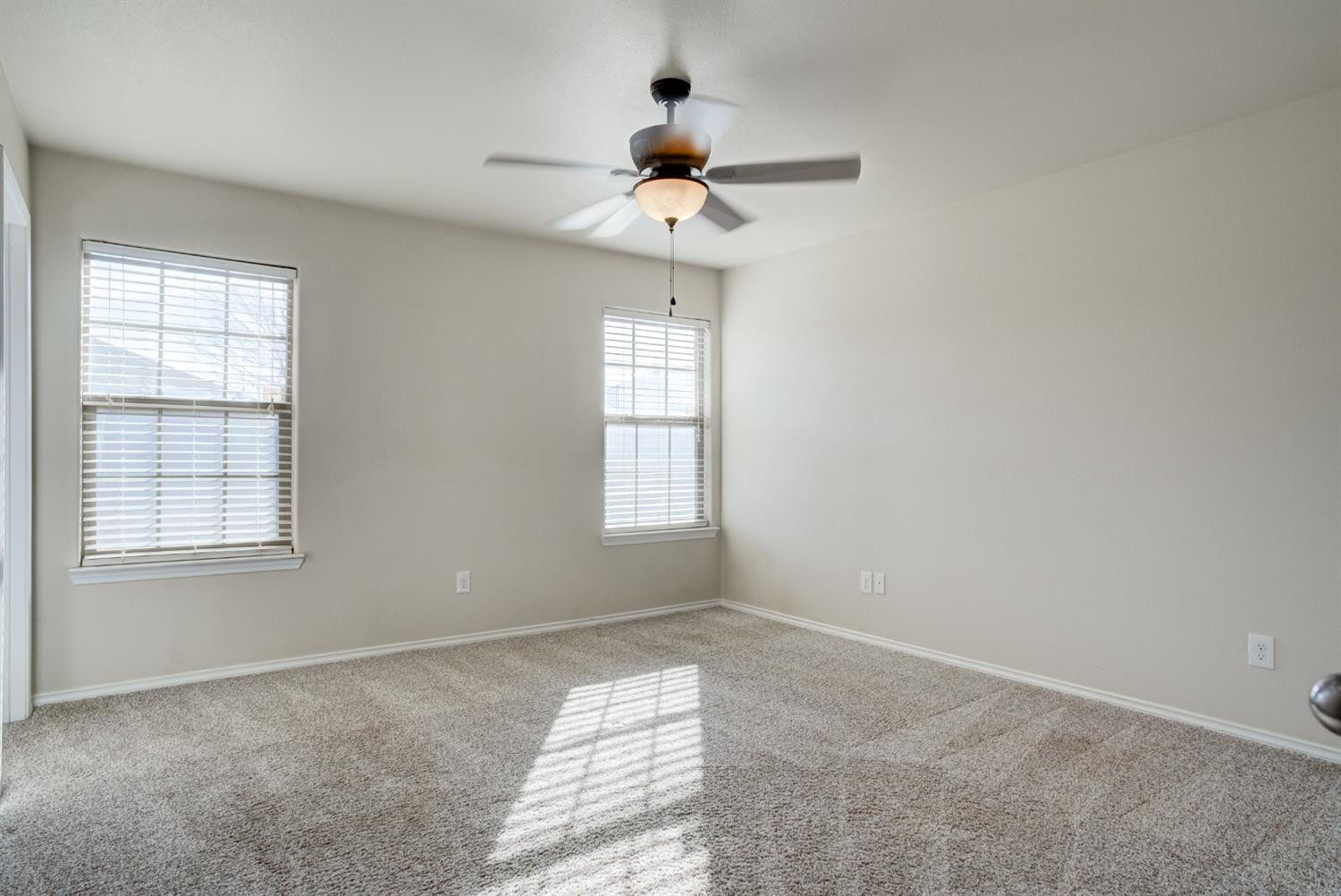 6921 95th Street Lubbock, TX 79424 - Photo 19 of 32 a bedroom with a chandelier fan and windows