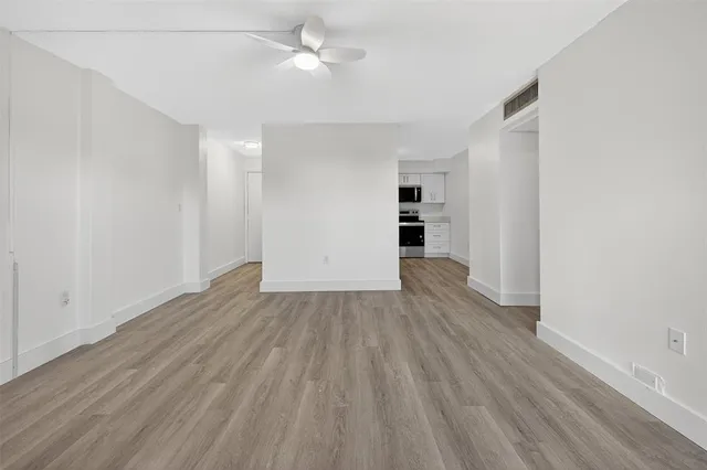 an empty room with wooden floor and ceiling fan