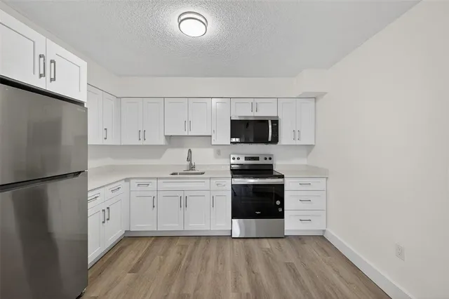a kitchen with stainless steel appliances a refrigerator stove and white cabinets