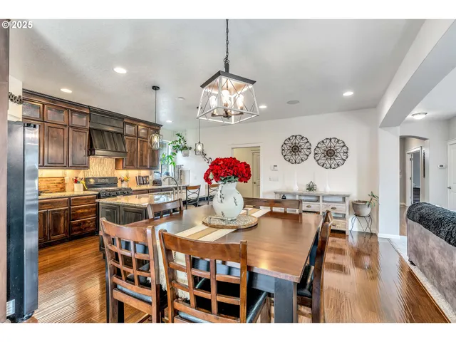 a dining room with wooden floor a chandelier a wooden table and chairs