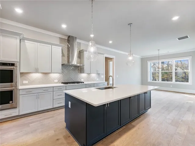 a large kitchen with stainless steel appliances kitchen island a large counter top and a wooden floors