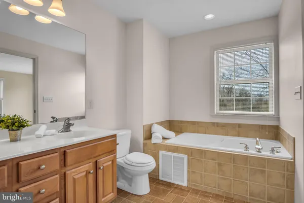 a bathroom with a bathtub sink vanity mirror and toilet