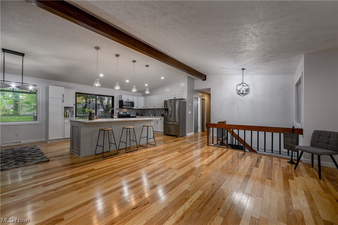 279 South Messner Road New Franklin, OH 44319 - Photo 5 of 30 Kitchen featuring light wood-type flooring, decorative light fixtures, stainless steel appliances, and beam ceiling