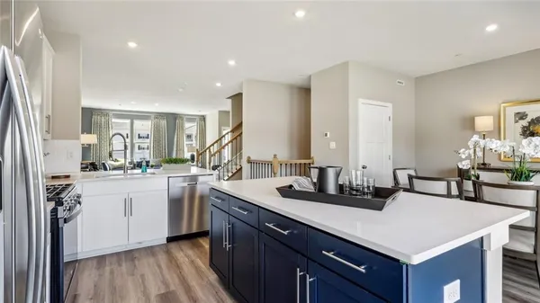 a kitchen with a sink dishwasher a stove a dining table and chairs with wooden floor