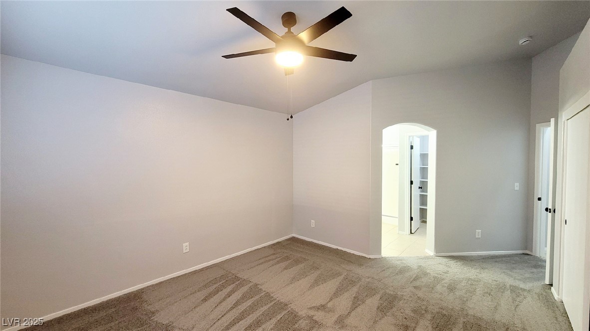 8840 Spinning Wheel Avenue Las Vegas, NV 89143 - Photo 13 of 24 Spare room featuring light carpet, arched walkways, ceiling fan, and vaulted ceiling