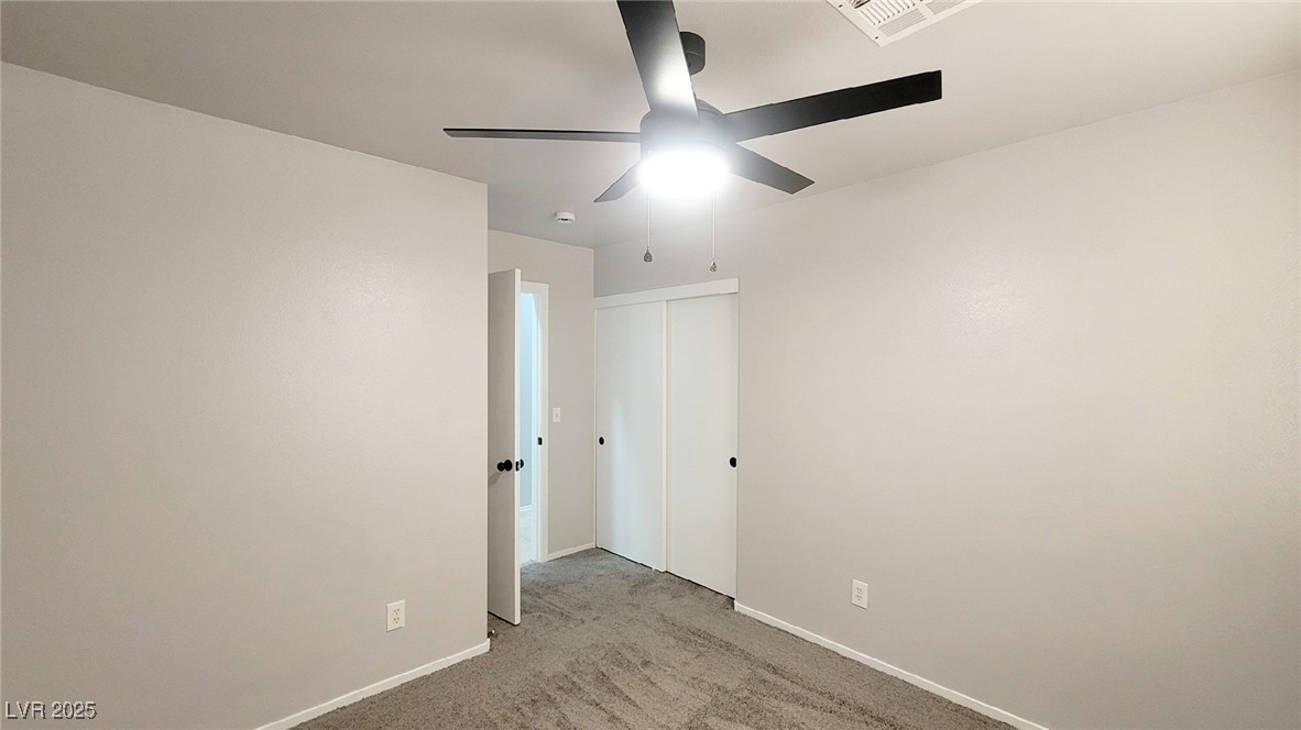 8840 Spinning Wheel Avenue Las Vegas, NV 89143 - Photo 16 of 24 Unfurnished bedroom with light carpet, a ceiling fan, and a closet