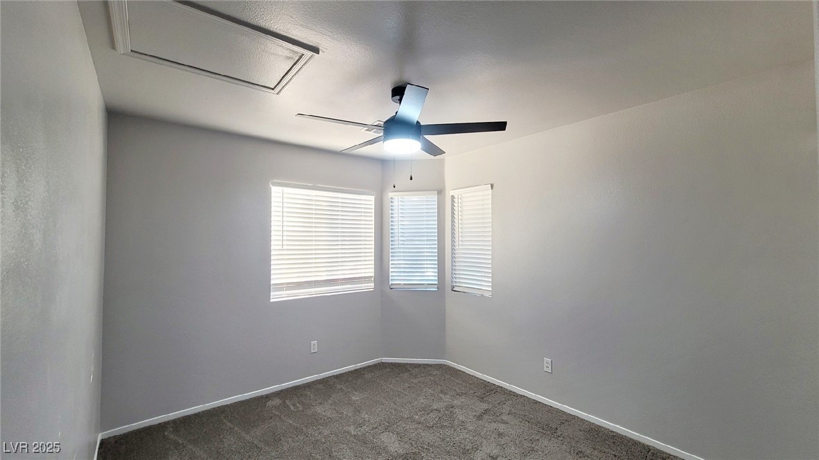 8840 Spinning Wheel Avenue Las Vegas, NV 89143 - Photo 19 of 24 Empty room with dark colored carpet, a ceiling fan, and attic access