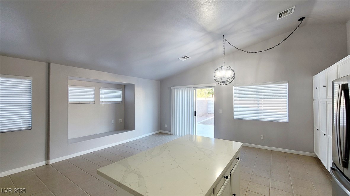 8840 Spinning Wheel Avenue Las Vegas, NV 89143 - Photo 7 of 24 Kitchen featuring white cabinets, a kitchen island, lofted ceiling, stainless steel fridge, and decorative light fixtures
