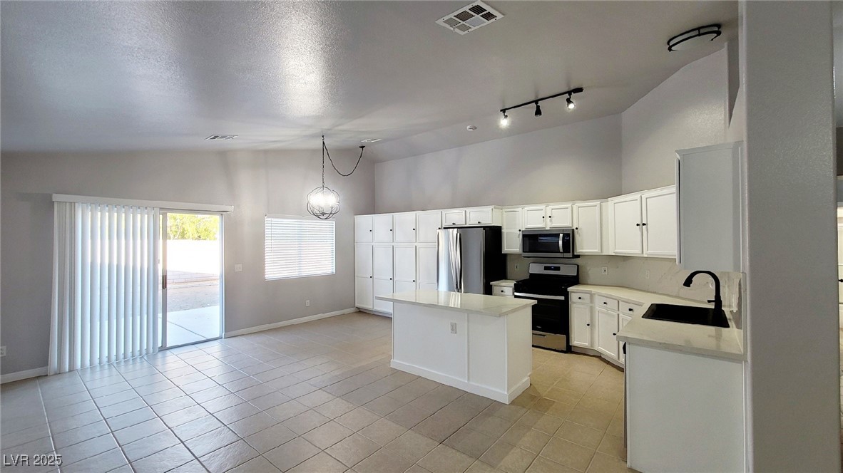 8840 Spinning Wheel Avenue Las Vegas, NV 89143 - Photo 8 of 24 Kitchen with appliances with stainless steel finishes, a kitchen island, high vaulted ceiling, white cabinets, and light tile patterned floors