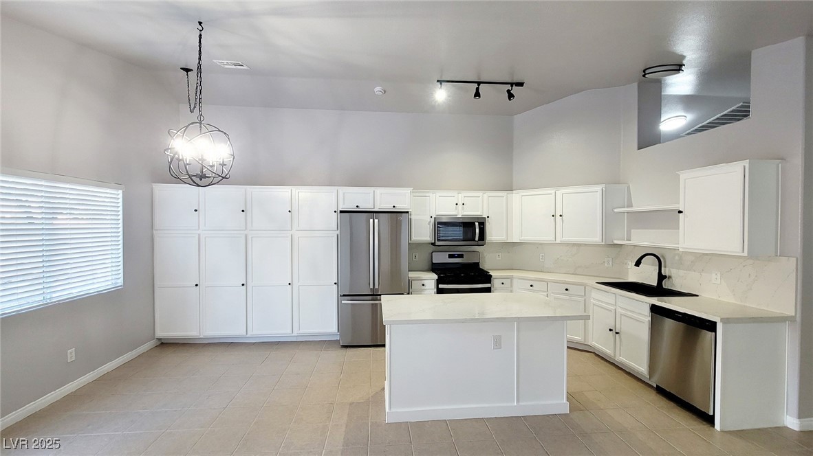 8840 Spinning Wheel Avenue Las Vegas, NV 89143 - Photo 9 of 24 Kitchen with stainless steel appliances, white cabinetry, backsplash, a towering ceiling, and open shelves