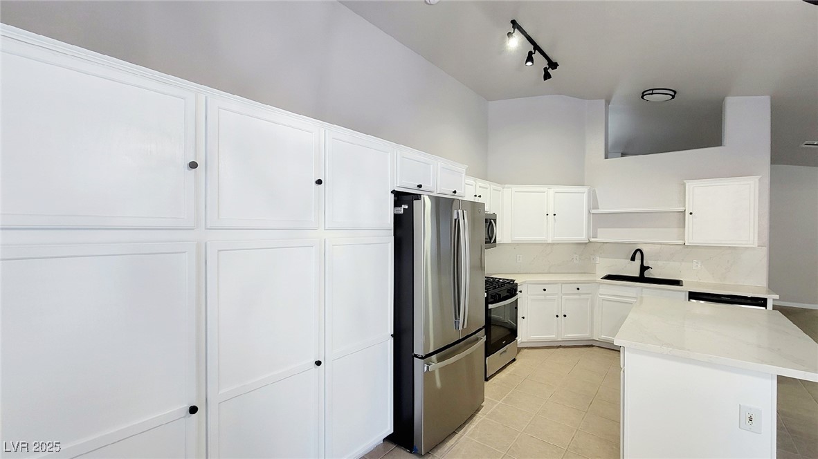 8840 Spinning Wheel Avenue Las Vegas, NV 89143 - Photo 10 of 24 Kitchen with open shelves, appliances with stainless steel finishes, tasteful backsplash, white cabinetry, and light tile patterned flooring