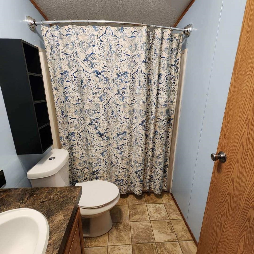 3595 Gainsville Road Mason, TN 38049 - Photo 23 of 28 a white toilet sitting next to a shower curtain