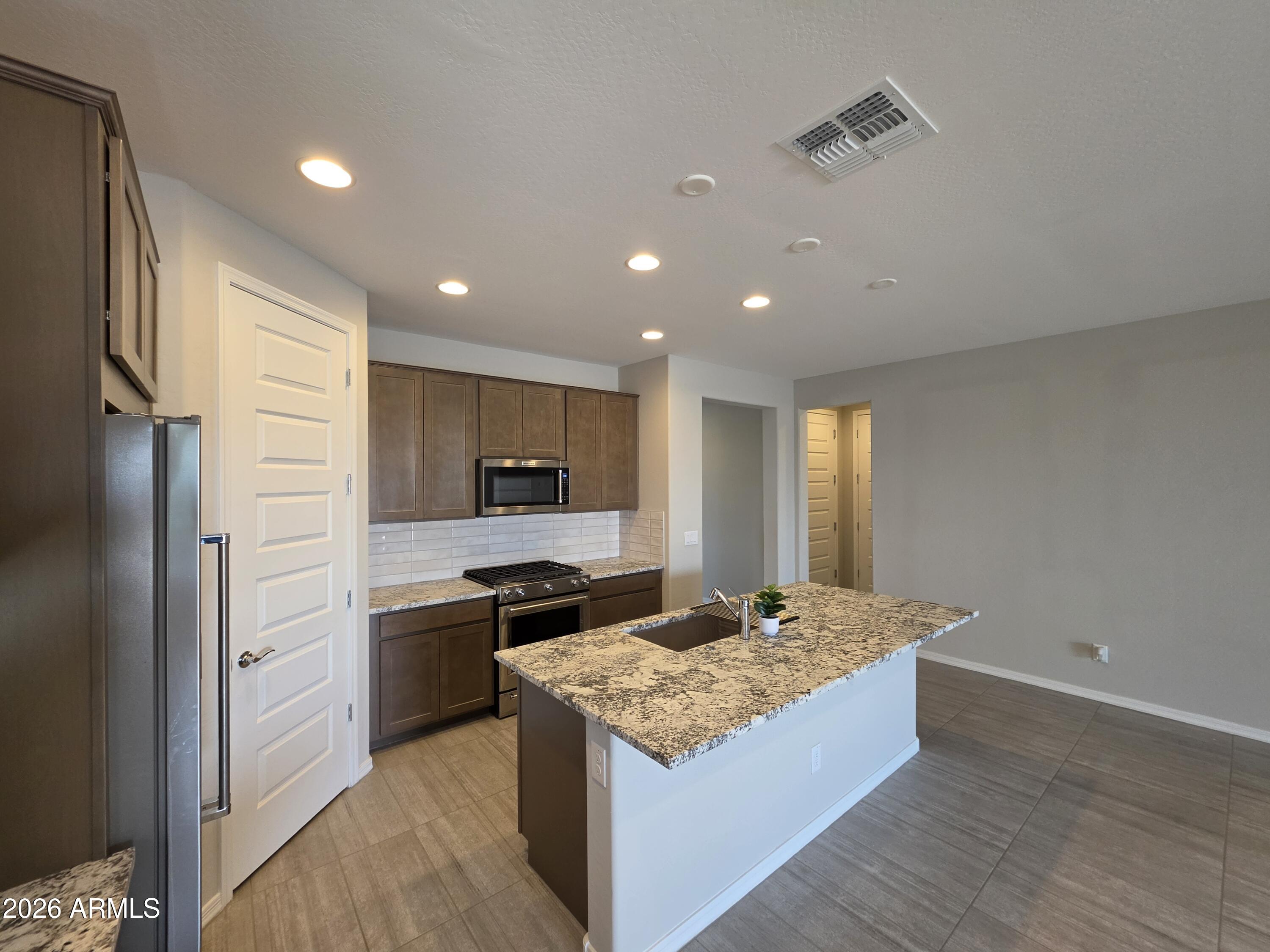7128 West Coles Road Laveen, AZ 85339 - Photo 3 of 38 a kitchen with kitchen island granite countertop a sink stove and refrigerator
