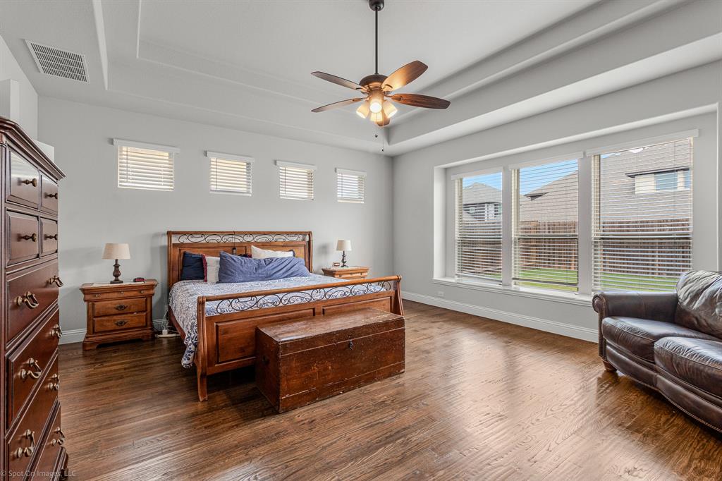 2139 Devonblue Drive Forney, TX 75126 - Photo 12 of 30 Primary bedroom featuring raised ceiling, hand scraped wood floors, ceiling fan and tons of natural lighting.