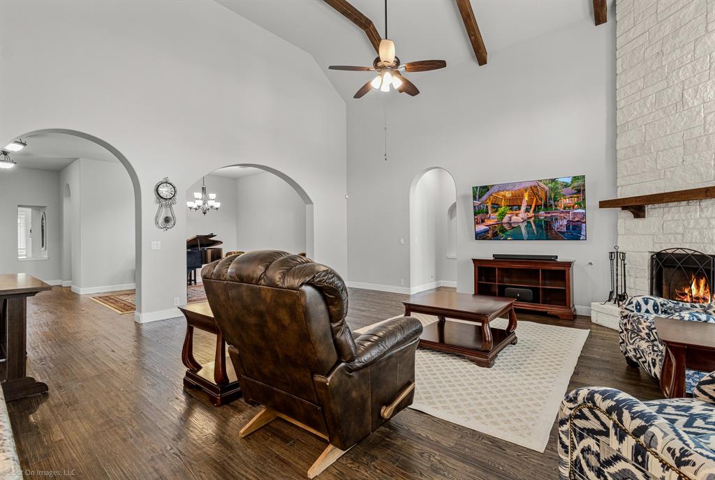 2139 Devonblue Drive Forney, TX 75126 - Photo 4 of 30 Living room with arched walkways, vaulted ceiling with wood beams, floor to ceiling stone fireplace, and hand scraped wood floors. Floor plugs