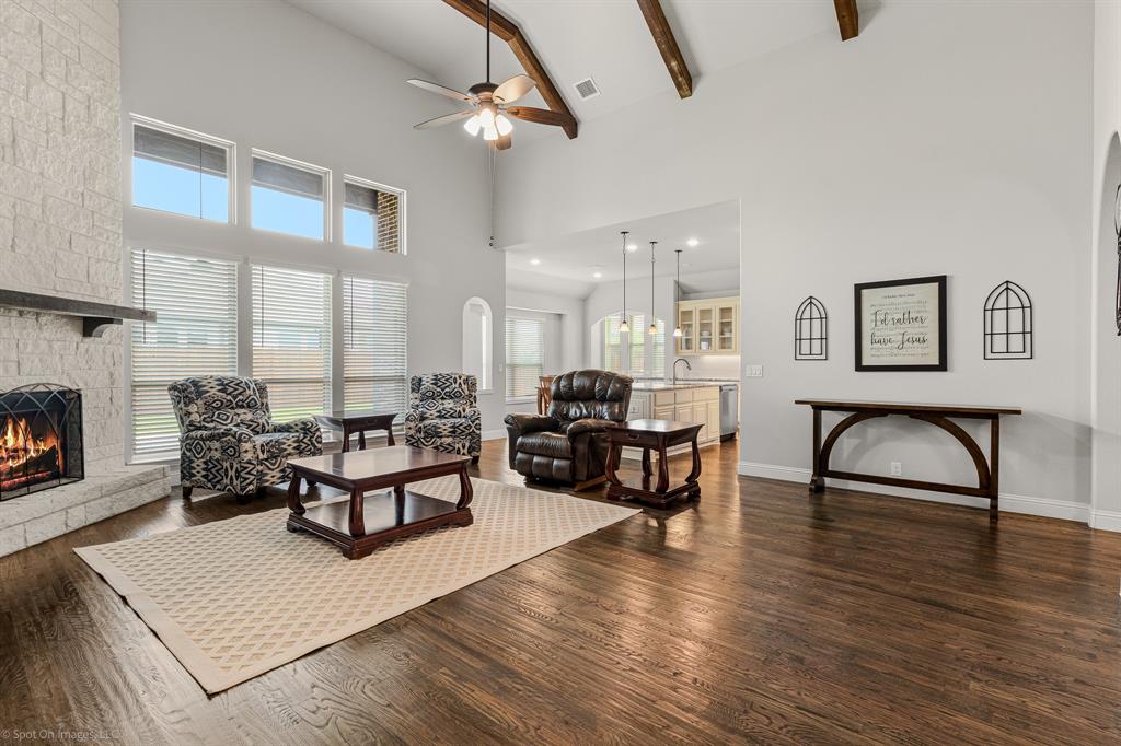 2139 Devonblue Drive Forney, TX 75126 - Photo 5 of 30 Living room with arched walkways, vaulted ceiling with wood beams, floor to ceiling stone fireplace, and hand scraped wood floors.