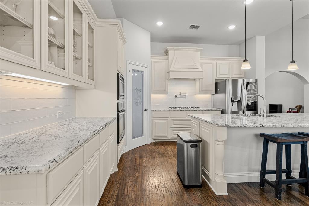 2139 Devonblue Drive Forney, TX 75126 - Photo 7 of 30 Deluxe Kitchen with Pot and Pan Drawers, Level 3 Granite Upgrade, Pendant lights over large island, under cabinet lighting, 36" Five Burner Gas Cooktop, Pot Filler above Range, Stainless Steel Convection Oven and Microwave, tons of cabinet space and breakfast area.