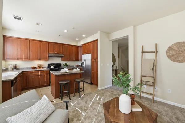 a kitchen with stainless steel appliances granite countertop a refrigerator a stove a sink a dining table and chairs with wooden floor