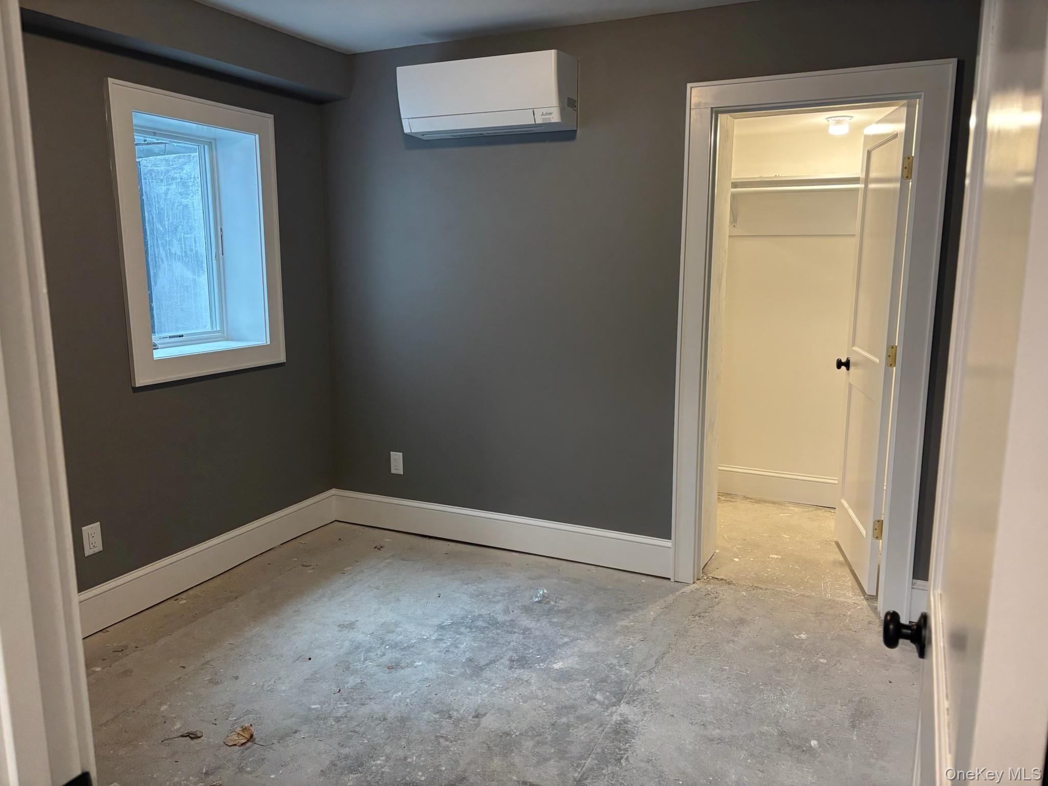 32 Western Avenue, Unit SUITE 3 Marlboro, NY 12542 - Photo 6 of 10 Unfurnished bedroom featuring a wall unit AC, unfinished concrete flooring, and a spacious closet