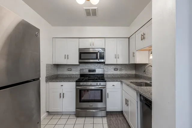a kitchen with granite countertop white cabinets white stainless steel appliances and a sink