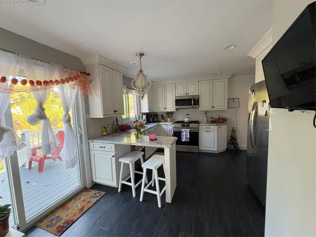 a kitchen with stainless steel appliances a stove a refrigerator a sink dishwasher a dining table and chairs with wooden floor