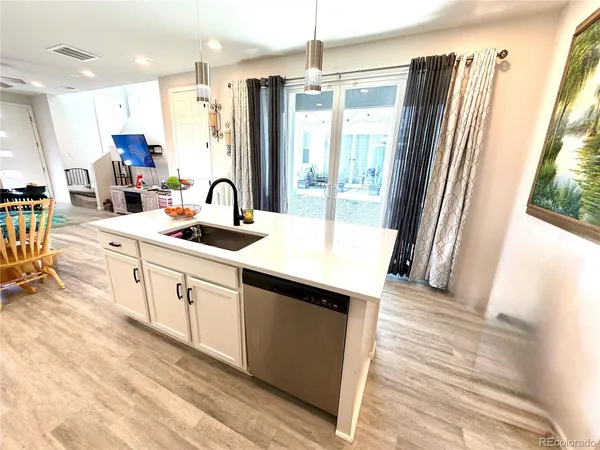 a kitchen with stainless steel appliances granite countertop a refrigerator a sink a stove and white cabinets with wooden floor