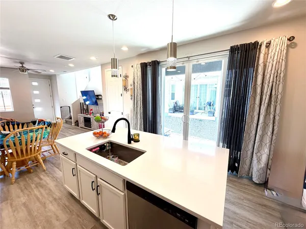 a kitchen with stainless steel appliances granite countertop a refrigerator a sink a stove and a dining table with wooden floor