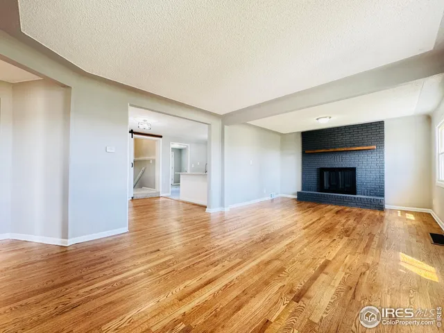 a view of empty room with wooden floor and fireplace