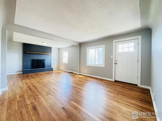 an empty room with wooden floor and fireplace