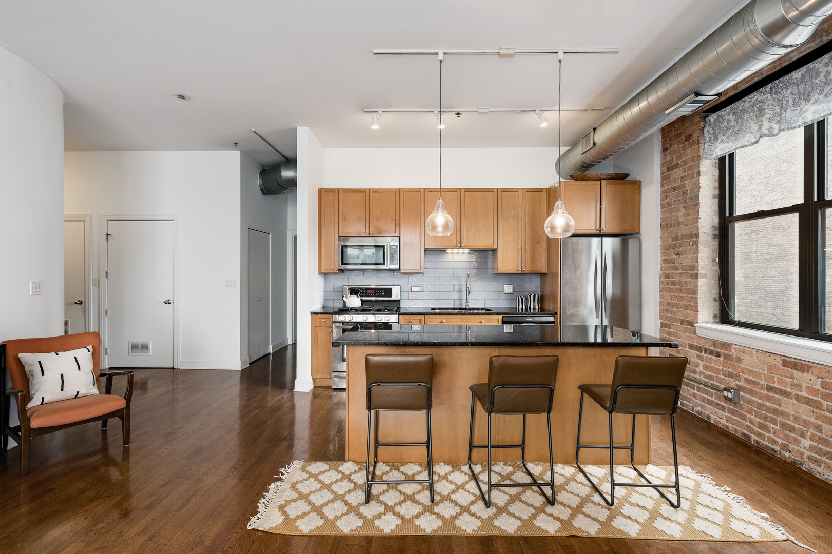 23 North Green Street, Unit 402 Chicago, IL 60607 - Photo 9 of 18 a kitchen with stainless steel appliances a dining table chairs sink and wooden floor