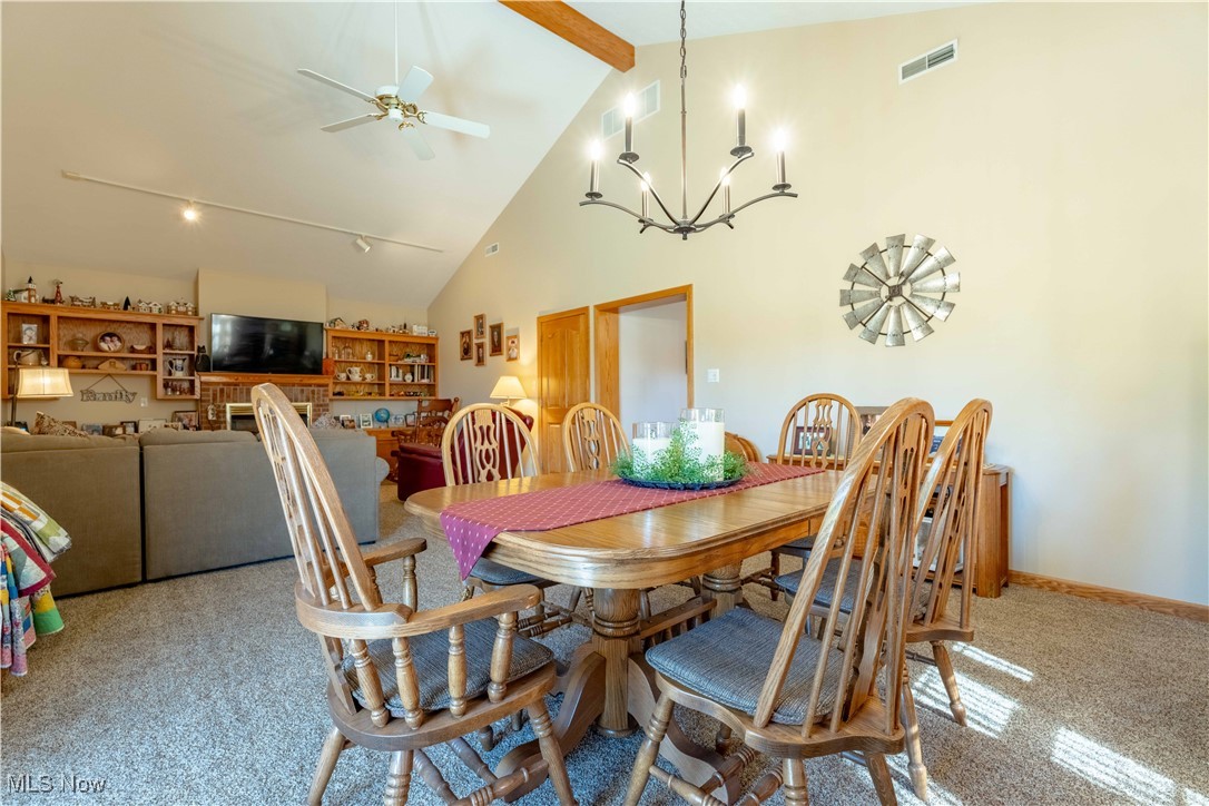 90480 Kilgore Ridge Road Scio, OH 43988 - Photo 14 of 39 Dining area with high vaulted ceiling, beamed ceiling, ceiling fan, a chandelier, and light colored carpet
