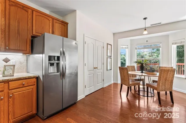 a kitchen with stainless steel appliances granite countertop a dining table chairs refrigerator and sink
