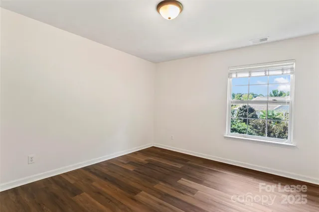 an empty room with wooden floor and window