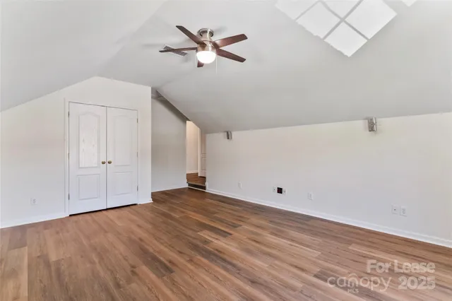 a view of empty room with wooden floor and ceiling fan