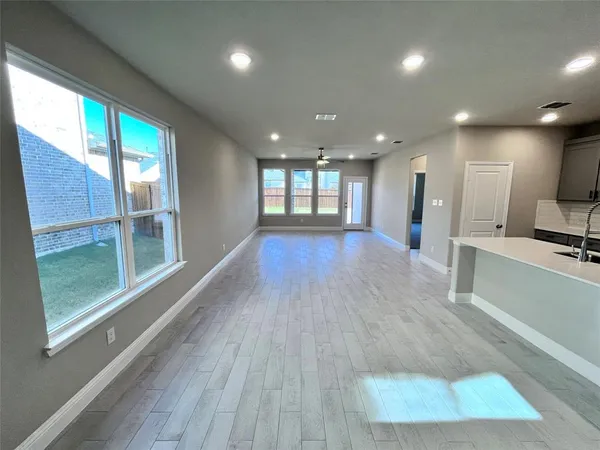 a view of a big room with wooden floor and windows