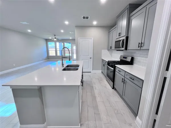 a large kitchen with stainless steel appliances a large counter top a stove a chimney a sink and a refrigerator