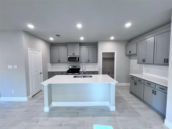 a large kitchen with stainless steel appliances a sink a stove a refrigerator cabinets and a window