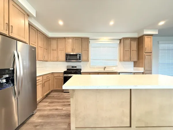 a large kitchen with a refrigerator a stove top oven a sink and dishwasher