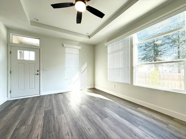 a view of an empty room with wooden floor and a window