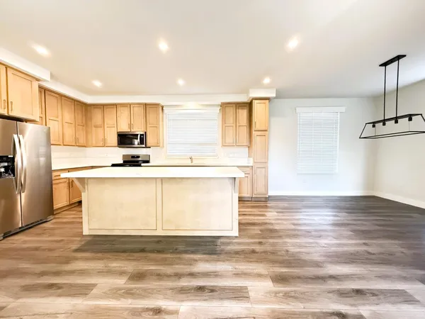 a kitchen with stainless steel appliances granite countertop a sink a stove a refrigerator with white cabinets and wooden floor