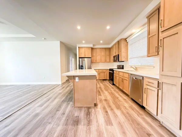 a large white kitchen with wooden floors stainless steel appliances