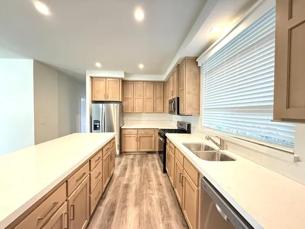 a kitchen with a sink a counter top space stainless steel appliances cabinets and a large window