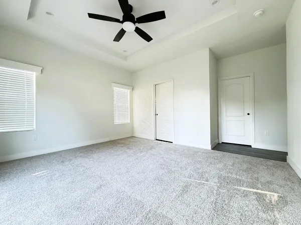 an empty room with chandelier fan and windows