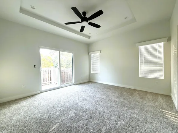 an empty room with ceiling fan and windows