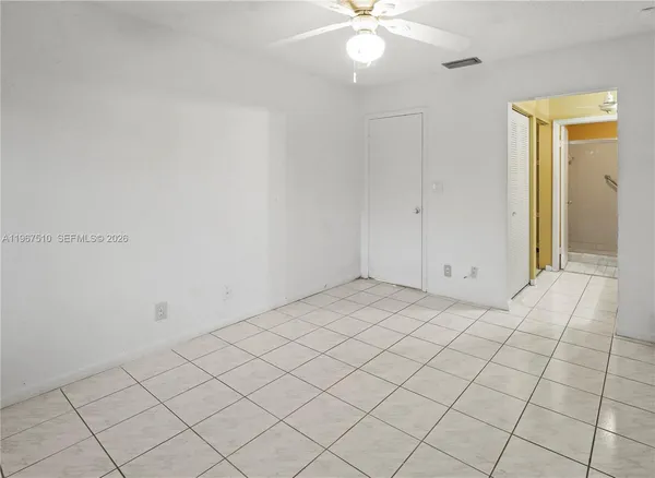 an empty room with a chandelier fan and glass door