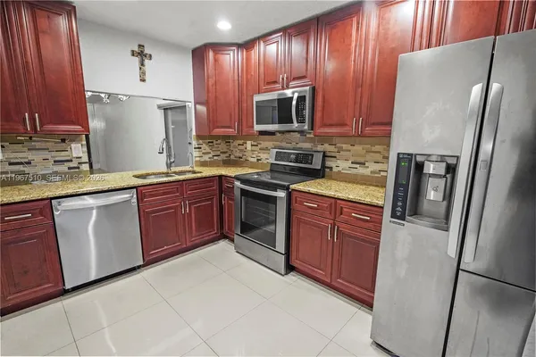 a kitchen with stainless steel appliances granite countertop a refrigerator stove a sink dishwasher and microwave