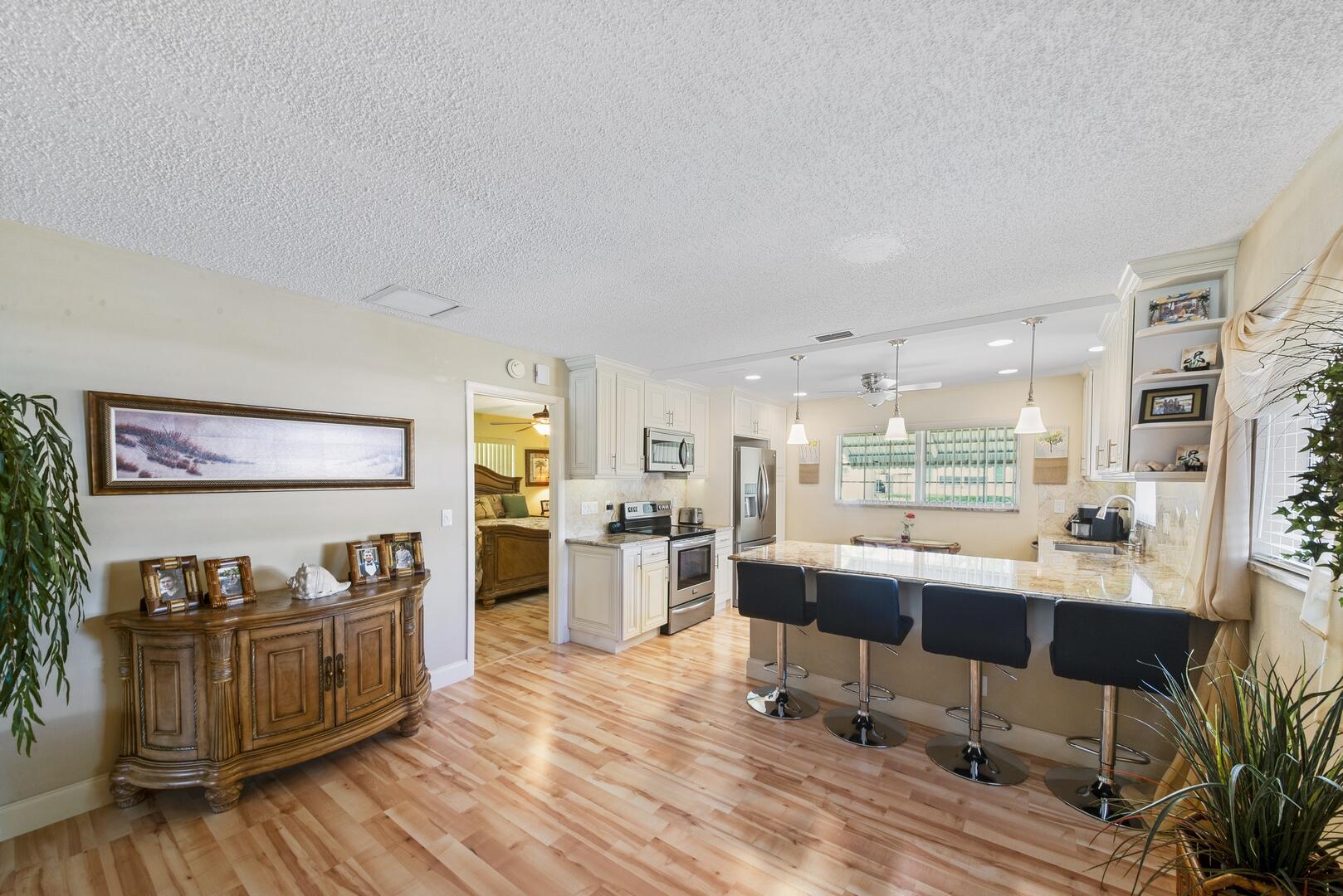 a large living room with stainless steel appliances kitchen island granite countertop furniture and a wooden floor