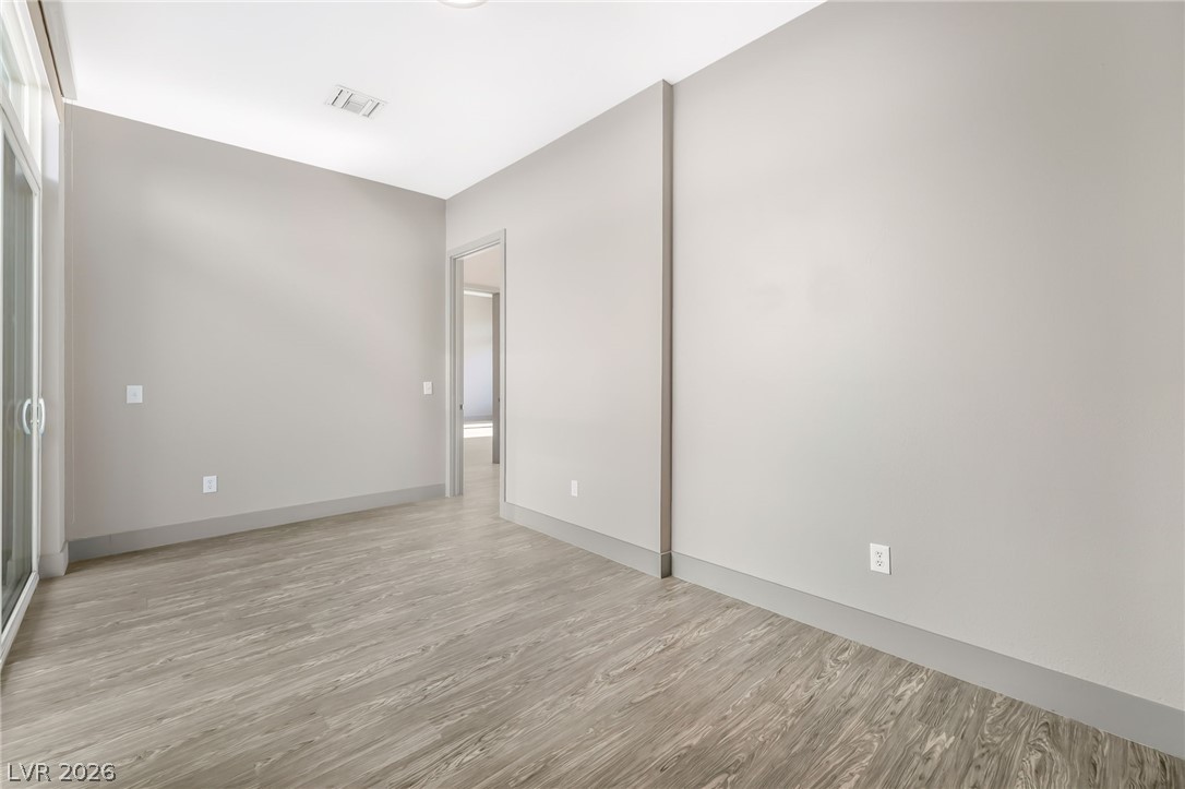 2775 West Pebble Road, Unit 505 Las Vegas, NV 89123 - Photo 21 of 26 Laminate flooring extends into an open concept layout, revealing a bright interior with tall ceilings.